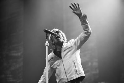 Black and white image from The Bon Jovi Experience, a musician sings into a microphone.